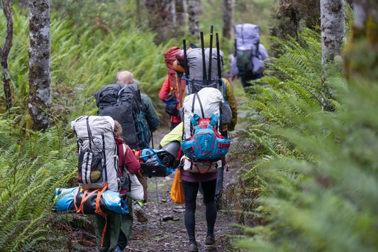 A group of packrafters hiking with fully loaded backpacks.